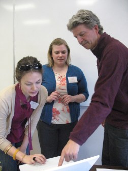 Teacher Leaders Andria Chase and Sarah Williams take a closer look at workshop info with Leadership team member Jeff Beaudry